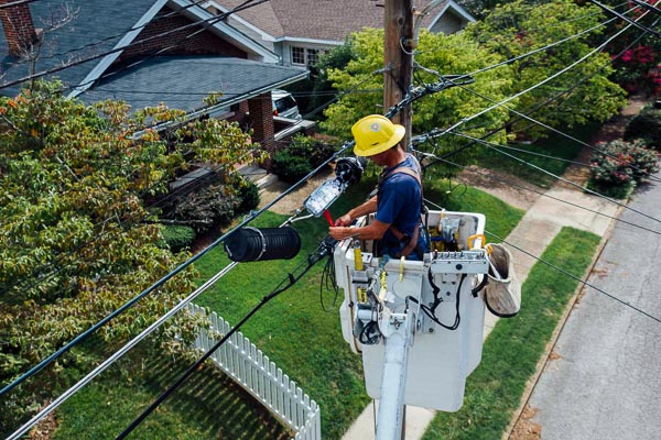 Utility lineman performs maintenance from a bucket.