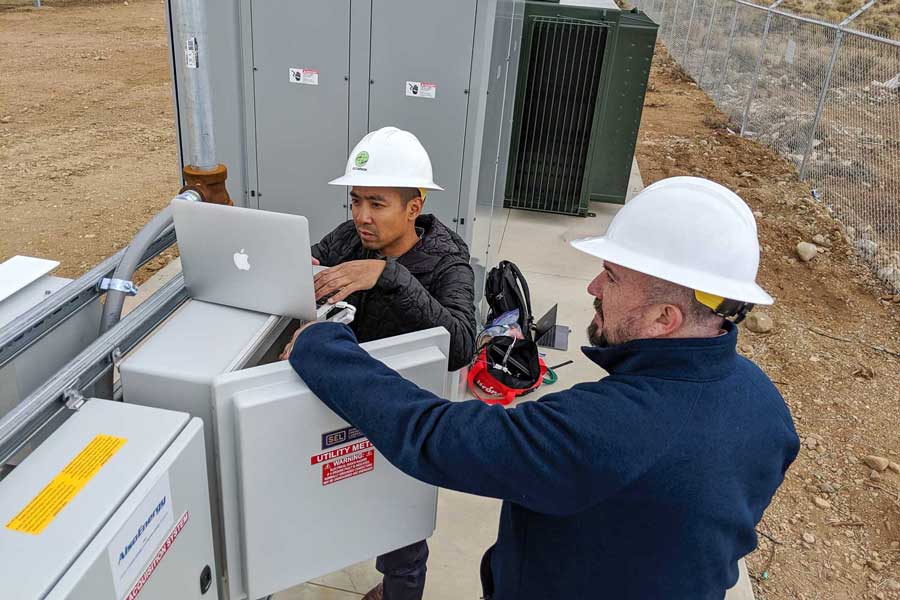 two workers with a computer at a substation