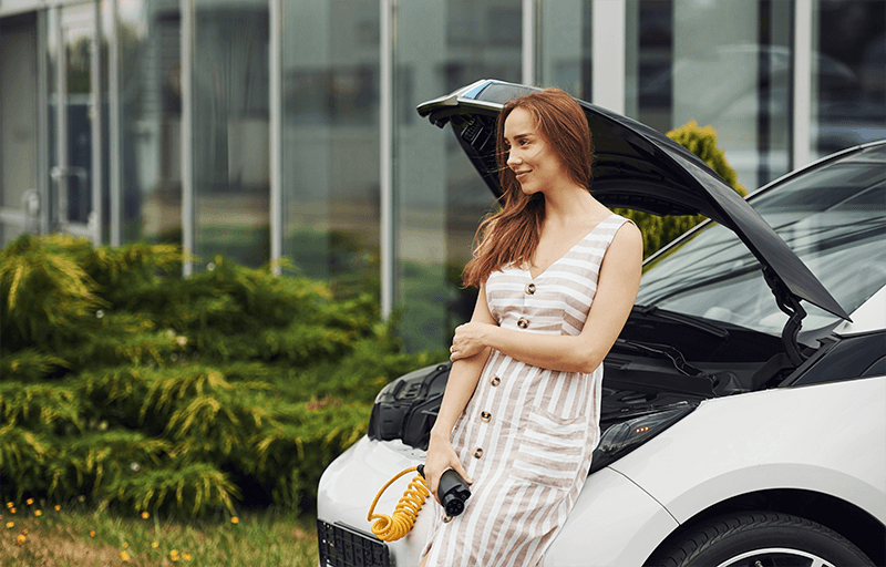 Woman smiles as waiting to plug in her EV